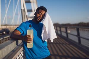 Porträt von müde jung Afroamerikaner Mann Wer Tücher das Schweiß von seine Gesicht nach Joggen. foto