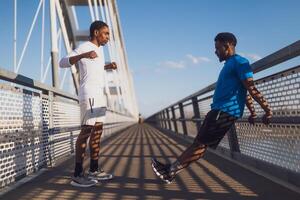 zwei Afroamerikaner freunde sind ausüben auf das Brücke im das Stadt. Sie sind Erwärmen oben zum Joggen. foto