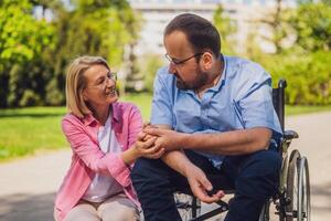 Mann im Rollstuhl ist Ausgaben Zeit mit seine Freund im Park. foto