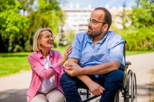 Mann im Rollstuhl ist Ausgaben Zeit mit seine Freund im Park. foto