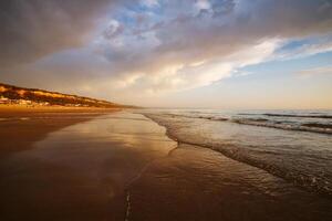 atlantisch Ozean Sonnenuntergang mit wogend Wellen beim fonte da telha Strand, Portugal foto