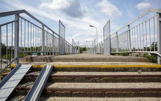 Eisenbahnbrücke mit Stufen, mit beeindruckenden Stufen in der Perspektive. Fußgängerüberweg überqueren. Brückentreppe, die einen Bahnsteig zum anderen am Bahnhof verbindet. foto