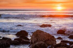 atlantisch Ozean Sonnenuntergang mit Wellen und Felsen. Costa da Caparica, Portugal foto