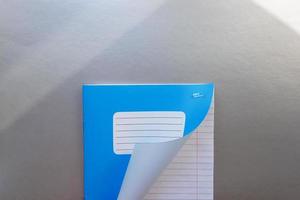 Designkonzept - Draufsicht auf eine hochwertige männliche Hand, die durch ein Blatt blau gestreiftes Notizbuch blättert. Ansicht von oben, Textfreiraum, flache Lage foto