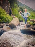 Frau tun Ashtanga Vinyasa Yoga Asana draußen beim Wasserfall foto