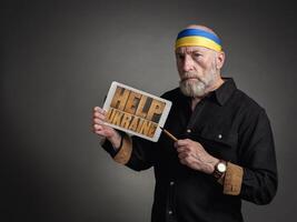 Hilfe Ukraine Wörter auf ein Tablette gehaltenen durch Senior Mann foto