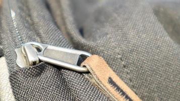 Reißverschluss schwarze Tasche Rucksack Textilzubehör. Nahaufnahme der Schließe. Textil, Metall und braunes Leder. foto