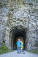 männlich Radfahrer mit ein falten Fahrrad auf katy Weg beim ein Tunnel in der Nähe von Rocheport, Missouri, Frühling Landschaft. das katy Weg ist 237 Meile Fahrrad Weg umgewandelt von ein alt Eisenbahn. foto