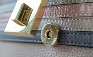 Nahaufnahme eines goldenen magnetischen Knopfverschlusses einer offenen, eleganten, modischen beige Leder-Umhängetasche für Damen. Zubehör, Detail. foto