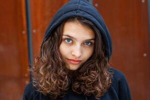 Weiß Brünette Teenager Mädchen mit lockig Haar posiert auf das Straße im das Stadt. foto