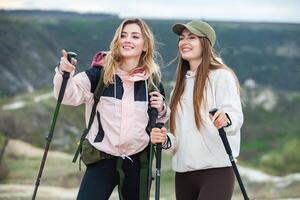 zwei jung Frauen Wandern im das Berge und Trinken Tee von ein Wasserkocher. reisen, Reisender. foto