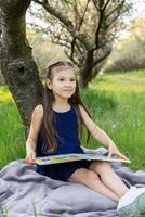 ein Kind Mädchen ist lesen ein Buch im das Park foto