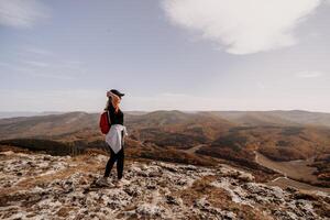 Frau auf Berg Gipfel suchen im schön Berg Senke im Herbst. Landschaft mit sportlich jung Frau, blau Himmel im fallen. wandern. Natur foto