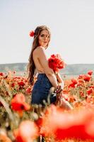 Frau Mohnblumen Feld. Porträt glücklich Frau mit lange Haar im ein Mohn Feld und genießen das Schönheit von Natur im ein warm Sommer- Tag. foto