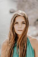 Frau Meer Grün Kleid. Porträt von ein glücklich Frau mit lange Haar im ein lange Minze Kleid posieren auf ein Strand mit Ruhe Meer Bokeh Beleuchtung auf sonnig Tag. Mädchen auf das Natur auf Blau Himmel Hintergrund. foto