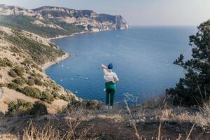 glücklich Frau Stehen mit ihr zurück im Natur im Sommer- mit öffnen Hände posieren mit Berge. Frau im das Berge, Öko freundlich, Sommer- Landschaft aktiv sich ausruhen foto