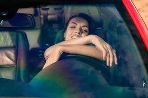 ein Frau ist Verlegung im ein Auto mit ihr Hände auf ihr Gesicht. sie ist lächelnd und sie ist entspannt. foto