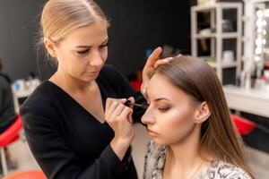 bilden Künstler Farben Wimpern zu ein Frau im ein Schönheit Salon. foto