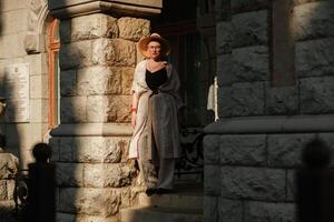 ein Frau im ein Hut im ein Weiß Outfit mit ein Tasche Spaziergänge um das Livadia Palast foto