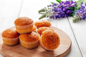 köstlich Muffins und lila Lupine Blumen auf Weiß hölzern Hintergrund. foto