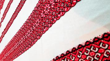 ukrainische Volkshandstickerei. gesticktes Ornament mit rot-schwarzen Fäden auf weißem Stoff. gesticktes Ornament aus schwarzem und rotem Faden. ethnische ukrainische Volksstickerei auf weißem Stoff. foto