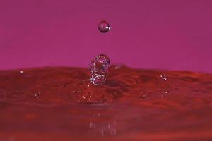 Spritzer durch den Aufprall eines Tropfens auf einen mit Wasser gefüllten Behälter foto