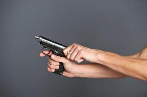 Hand mit Gewehr isoliert auf grau Hintergrund foto