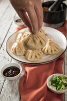 schließen oben zu kaukasisch chinkali Knödel Gericht serviert auf Platte. Hintergrund mit Zutaten und verstreut Gewürze foto