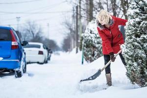 Frau schaufelt ihren Parkplatz foto