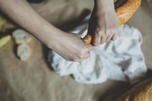 Essen Konzept. Hand Klicken ein Brot. Schneiden Brot. oben Sicht. kostenlos Raum zum Text foto