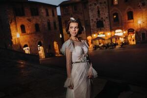 ein Braut im ein Weiß Kleid im das alt Stadt, Dorf von san gimignano.a Mädchen Spaziergänge um das Stadt im italien.toskana. foto