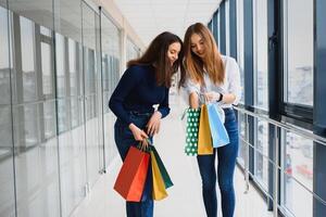 zwei Freundinnen auf Einkaufen gehen auf Einkaufen Center mit Taschen foto