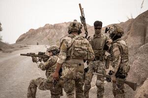 Soldaten im tarnen Uniformen Zielen mit ihr Gewehre bereit zu Feuer während Militär- Betrieb im das Wüste Soldaten Ausbildung im ein Militär- Betrieb foto