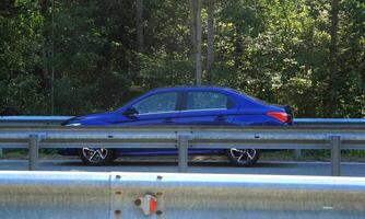 Auto auf das Straße hinter das Metall Autobahn Zaun foto