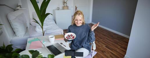 Porträt von jung Frau reden zu Publikum, Aufzeichnung vlog auf Digital Kamera, zeigen ihr Frühstück, reden Über gesund Essen und Lebensstil foto