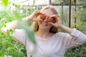 lächelnd Landwirtschaft Arbeiter halten Tomaten Über Augen im Gewächshaus. frisch saisonal Gemüse Ernte. Essen produzieren und Anbau. nachhaltig Landwirtschaft foto