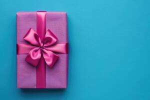 groß Geschenk Box eingewickelt im Fuchsie Farbe glänzend Papier mit Band Bogen auf Es. lebendig Blau Hintergrund mit Platz zum Text auf richtig Seite. glücklich Ferien oder Einkaufen Verkauf. foto