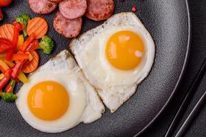 köstlich nahrhaft Frühstück mit gebraten Eier, Wurst, gedämpft Gemüse foto