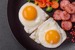 köstlich nahrhaft Frühstück mit gebraten Eier, Wurst, gedämpft Gemüse foto