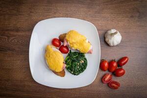 traditionell Omelett mit Gemüse, Spinat, Tomaten und Kräuter auf ein hölzern Tisch. klassisch europäisch Frühstück. foto