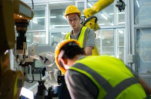 ein Techniker leidet ein Hand Unfall während Arbeiten mit ein Roboter Arm im ein Fabrik mit Mitarbeiter Bereitstellung Hilfe foto