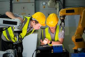 ein Techniker leidet ein Hand Unfall während Arbeiten mit ein Roboter Arm im ein Fabrik mit Mitarbeiter Bereitstellung Hilfe foto