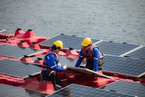 Photovoltaik Ingenieure Arbeit auf schwebend Photovoltaik. prüfen und Reparatur das Solar- Panel Ausrüstung schwebend auf das Wasser. foto