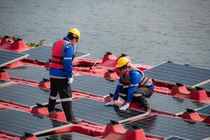 Photovoltaik Ingenieure Arbeit auf schwebend Photovoltaik. prüfen und Reparatur das Solar- Panel Ausrüstung schwebend auf das Wasser. foto