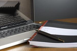 Telefon, Laptop und leeres Notebook auf dem Schreibtisch foto