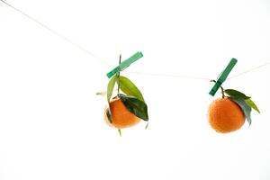 Orange Mandarin mit ein Grün Blatt hängend auf ein Zeichenfolge auf ein Weiß Hintergrund foto