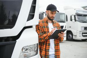 LKW Treiber Überprüfung Sendung aufführen während Stehen auf Parkplatz Menge von Verteilung Warenhaus foto