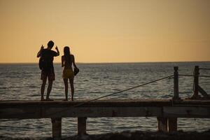 bayahibe dominikanisch Republik 13 Dezember 2019 jung Paar im Liebe auf das Seebrücke beim Sonnenuntergang foto