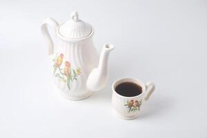 ein Tasse von Süss Tee mit ein Keramik Teekanne mit ein Vogel auf ein Weiß Hintergrund foto