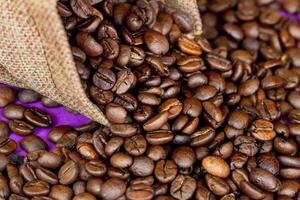 Kaffee Bohnen im ein Sackleinen Tasche auf das lila Hintergrund foto